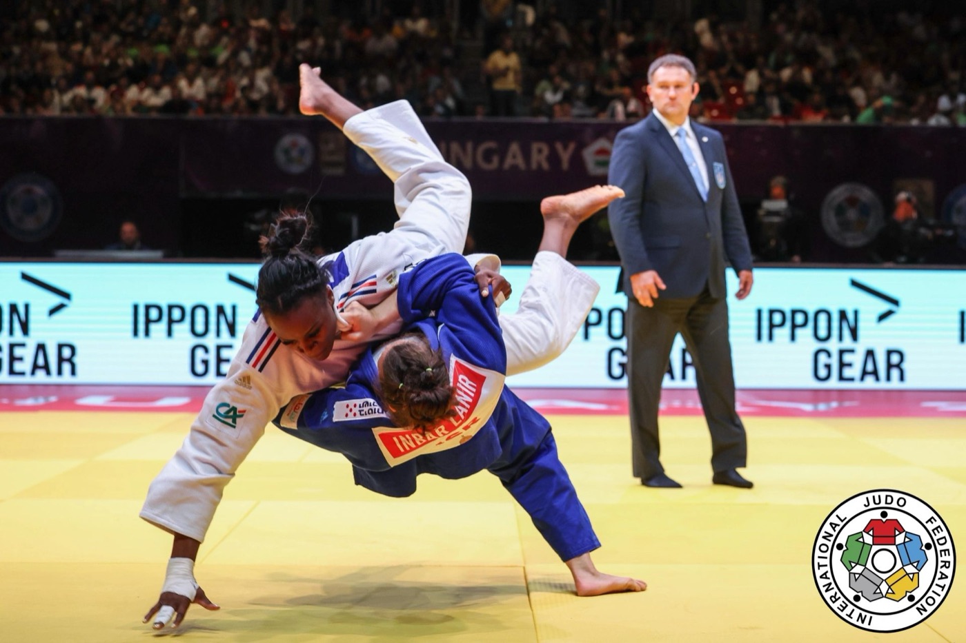 Inbar Lanir in a blue judogi throwing an opponent in a white judogi during an international judo final.